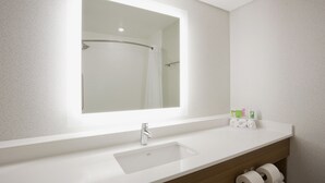 A modern bathroom with a white sink, a large mirror, and a shower area. - Holiday Inn Express & Suites Minneapolis – West End by IHG (Golden Valley)