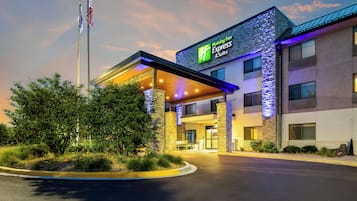 A Holiday Inn Express & Suites with a stone facade and a covered entrance.