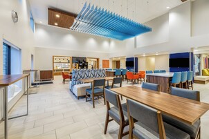 Un comedor moderno con mesas y sillas de madera, una estación de café y un revestimiento de pared estampado.