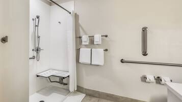 A modern bathroom with a shower, a grab bar, a towel rack, and a toilet paper holder.