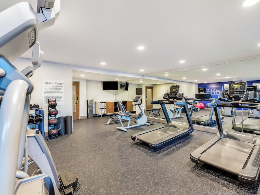 Un gimnasio con cintas de correr, pelotas de ejercicio y máquinas de pesas.