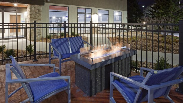 An outdoor patio with a fire feature, seating, and a view of the building in the background. - Holiday Inn Express & Suites Minneapolis – West End by IHG (Golden Valley)