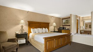 A hotel room with a wooden bed, two bedside tables with lamps, a chair, a bathroom with a bathtub, and a large mirror. - Days Inn by Wyndham Rapid City (Rapid City)