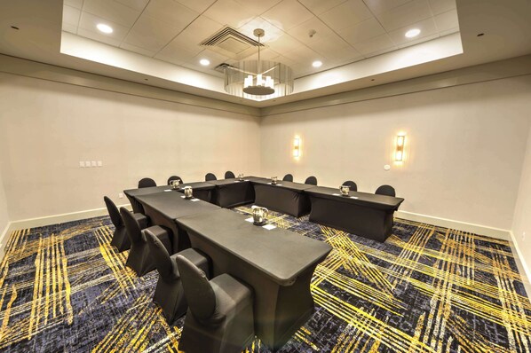 A conference room with a long table, chairs, and a patterned carpet.