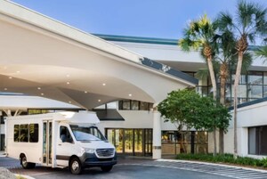Un edificio moderno con techo curvo y una camioneta blanca estacionada adelante.