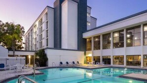 A hotel with a swimming pool, outdoor seating, and a modern building facade. - Wyndham Jacksonville Hotel & Conference Center (Jacksonville)