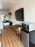 Una cocina compacta con microondas, refrigerador y comedor con mesa y sillas.