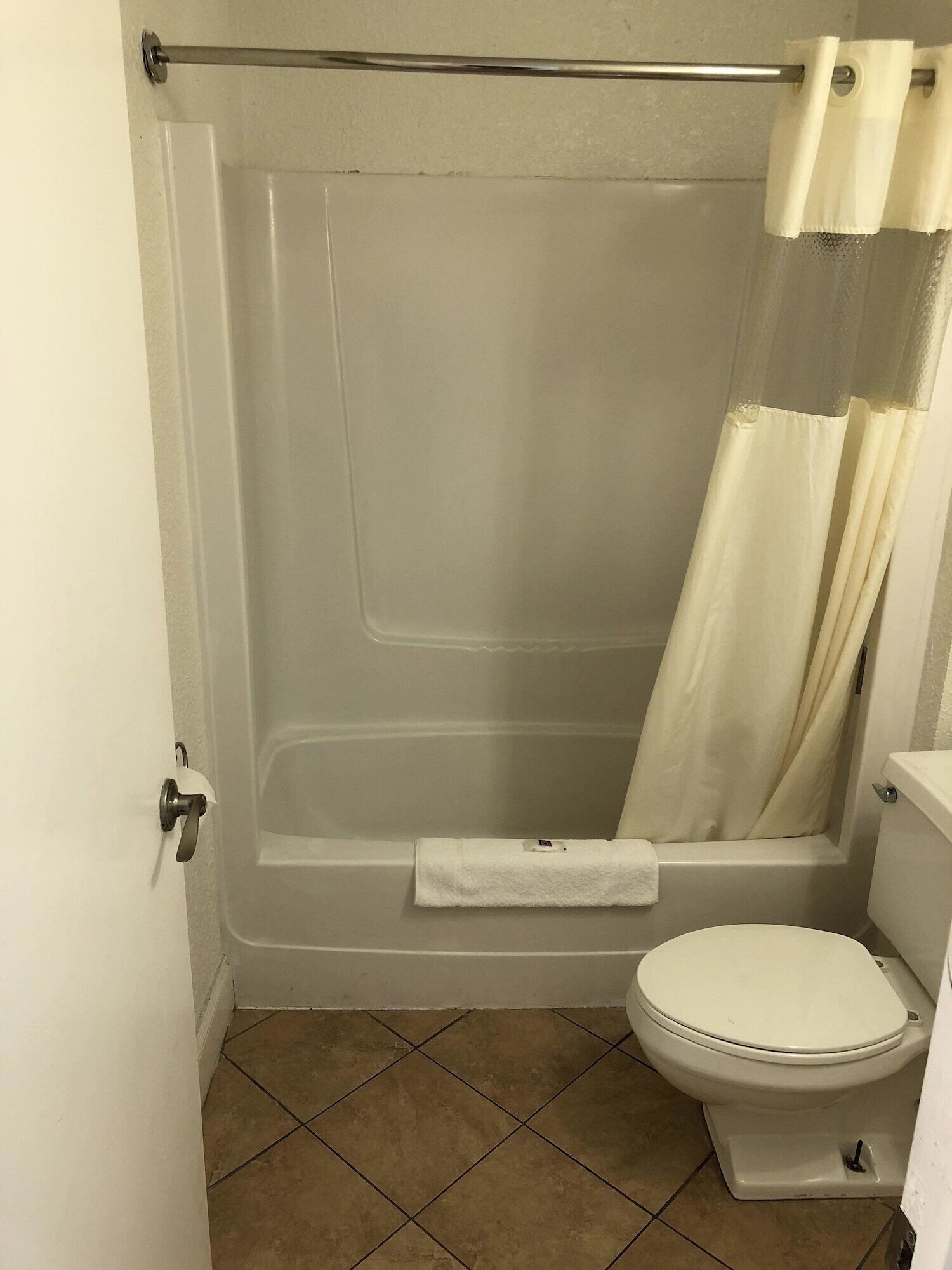 A bathroom with a bathtub, toilet, and a towel rack.