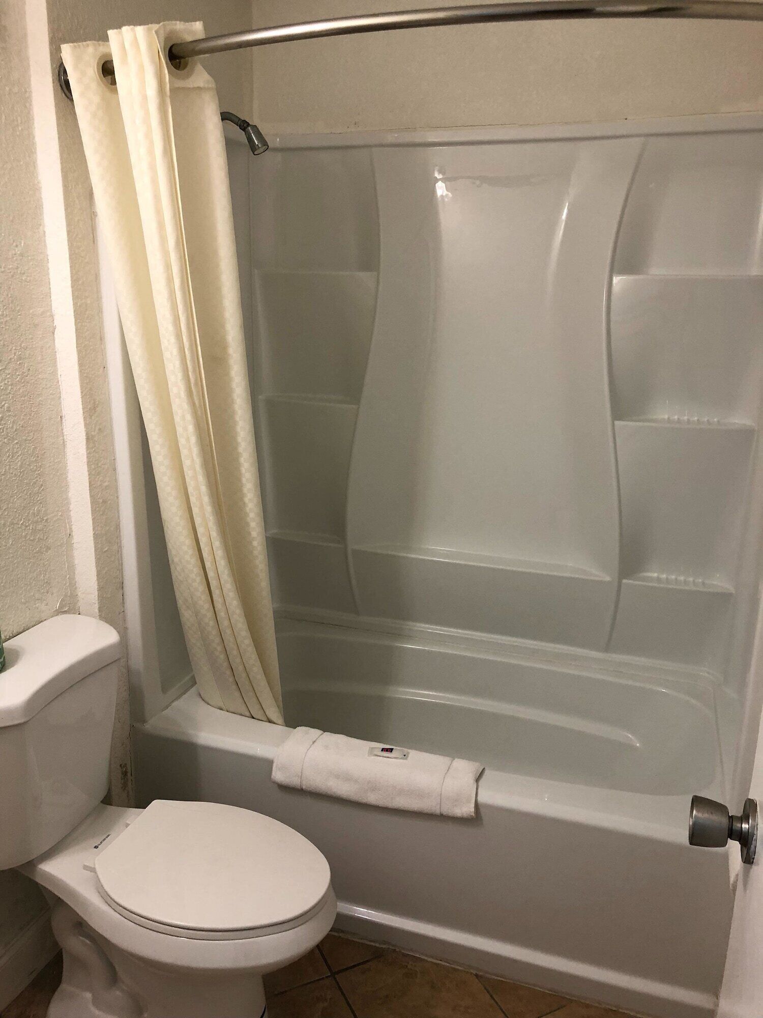 Ein Badezimmer mit einer weißen Toilette, einer Duschkabine und einem Handtuch an der Wand.