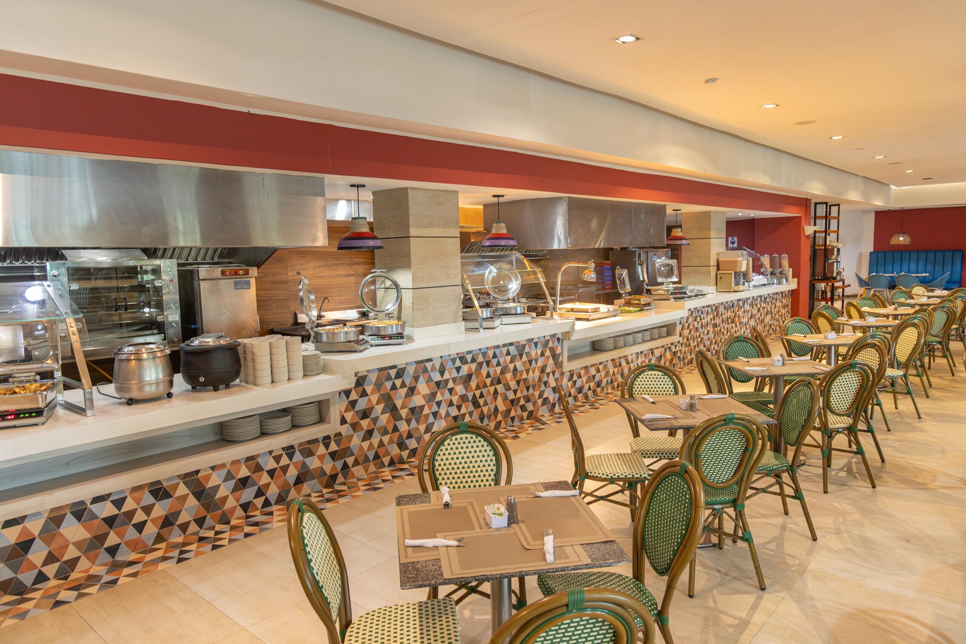 Il s’agit d’un restaurant proposant un buffet, avec un long comptoir, plusieurs points de service et une grande variété de plats. Plusieurs tables et chaises sont disposées pour accueillir les clients.