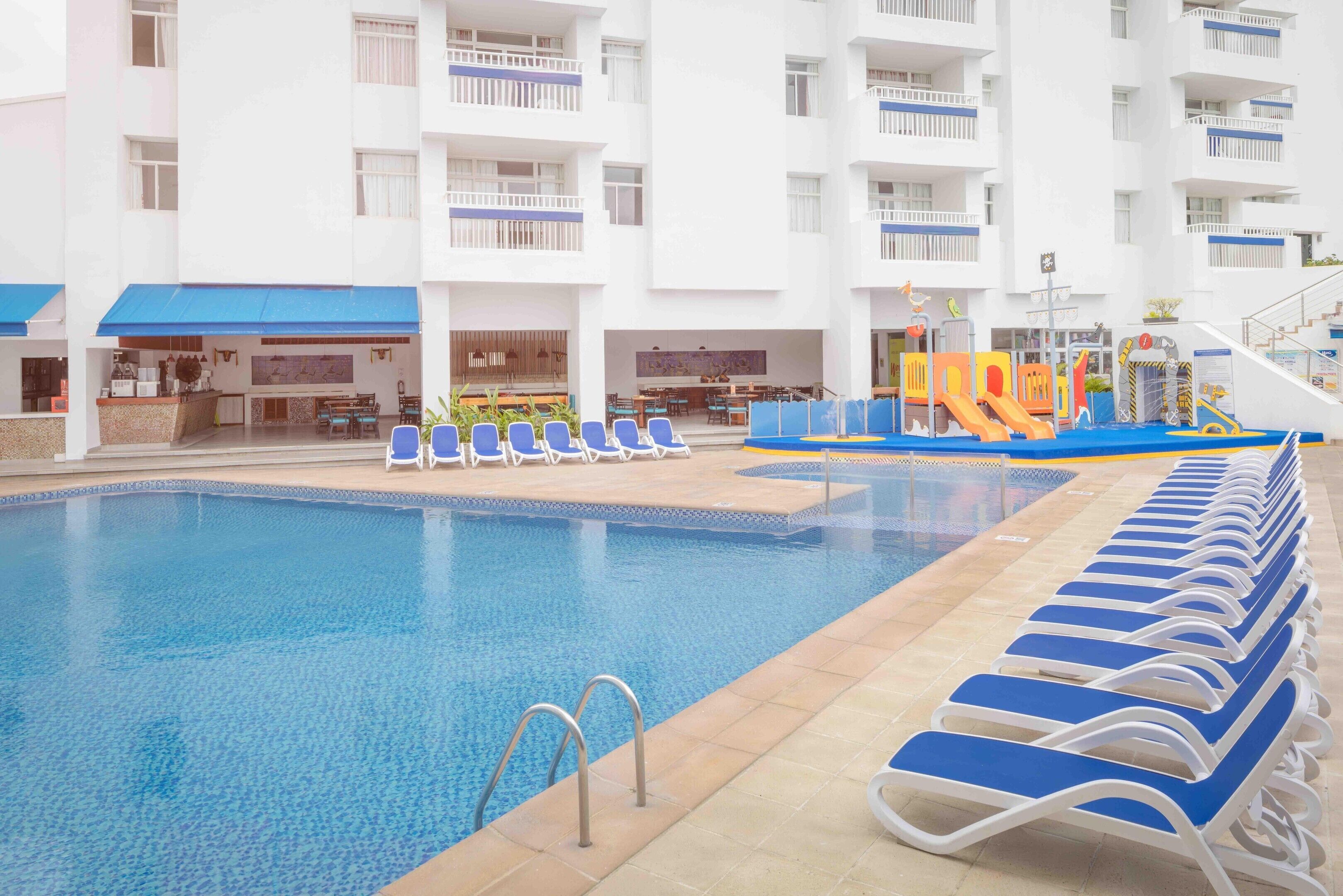A swimming pool with lounge chairs and a children's play area.