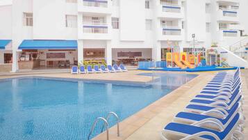 A swimming pool with lounge chairs and a children's play area.