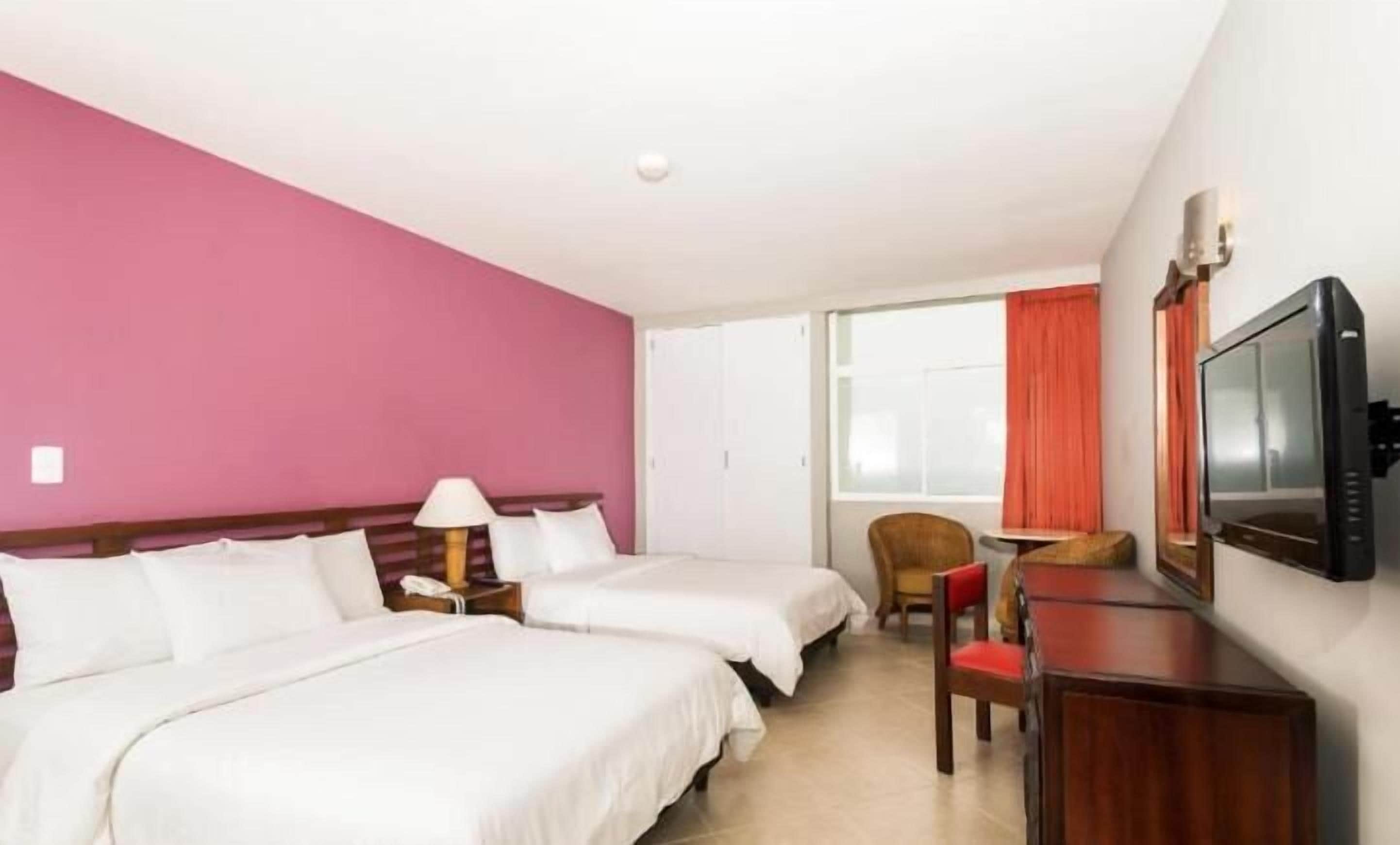 Een hotelkamer met twee bedden, een televisie, een bureau en een stoel.