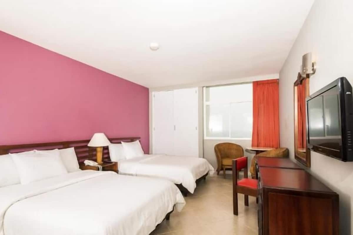A hotel room with two beds, a TV, a desk, and a chair.