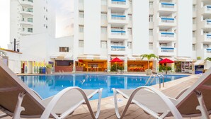 Ein Poolbereich mit Liegestühlen, einem Pool und einem Gebäude mit Balkonen.