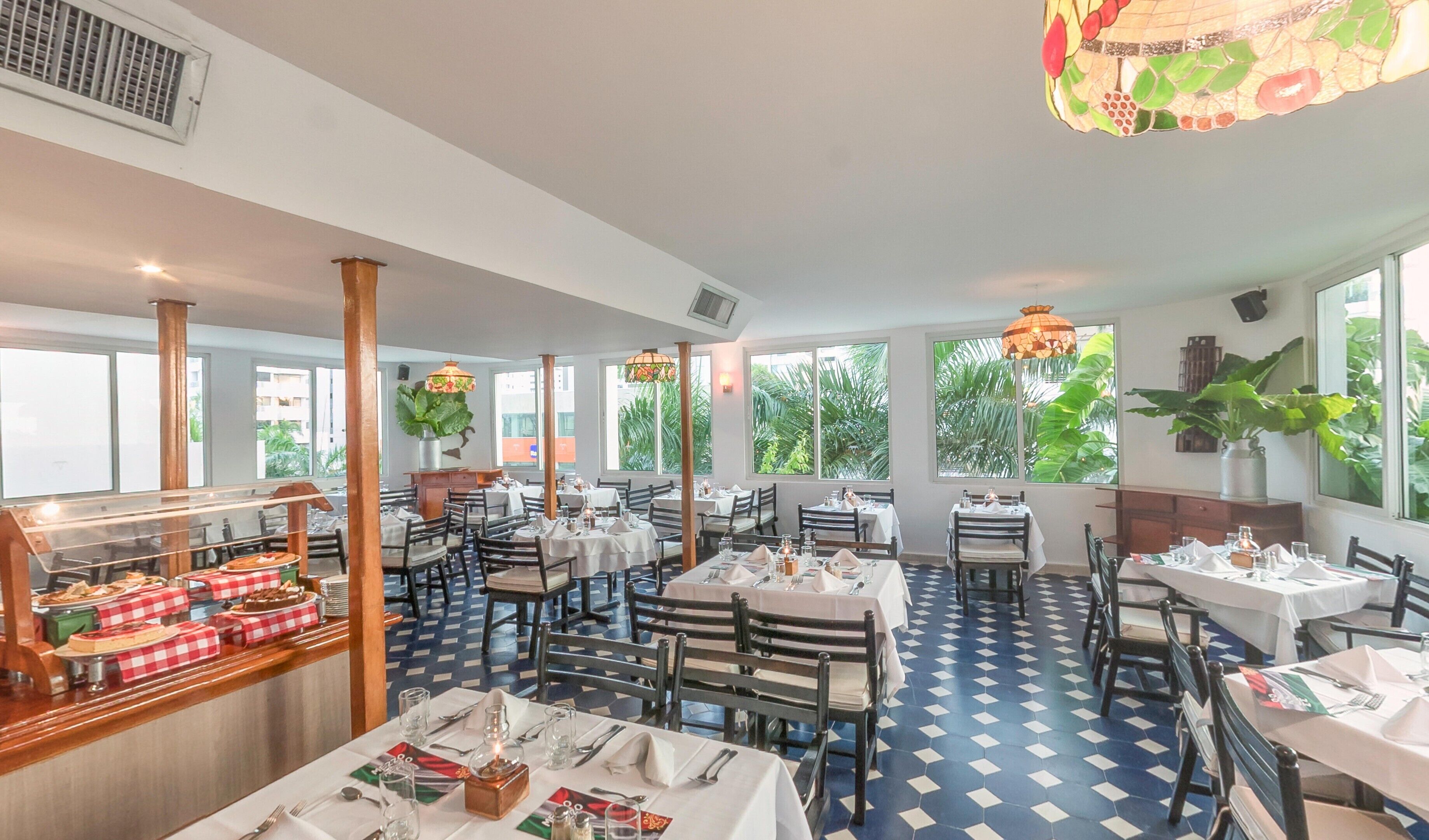 A restaurant with multiple tables and chairs, large windows, and a checkered tablecloth display.