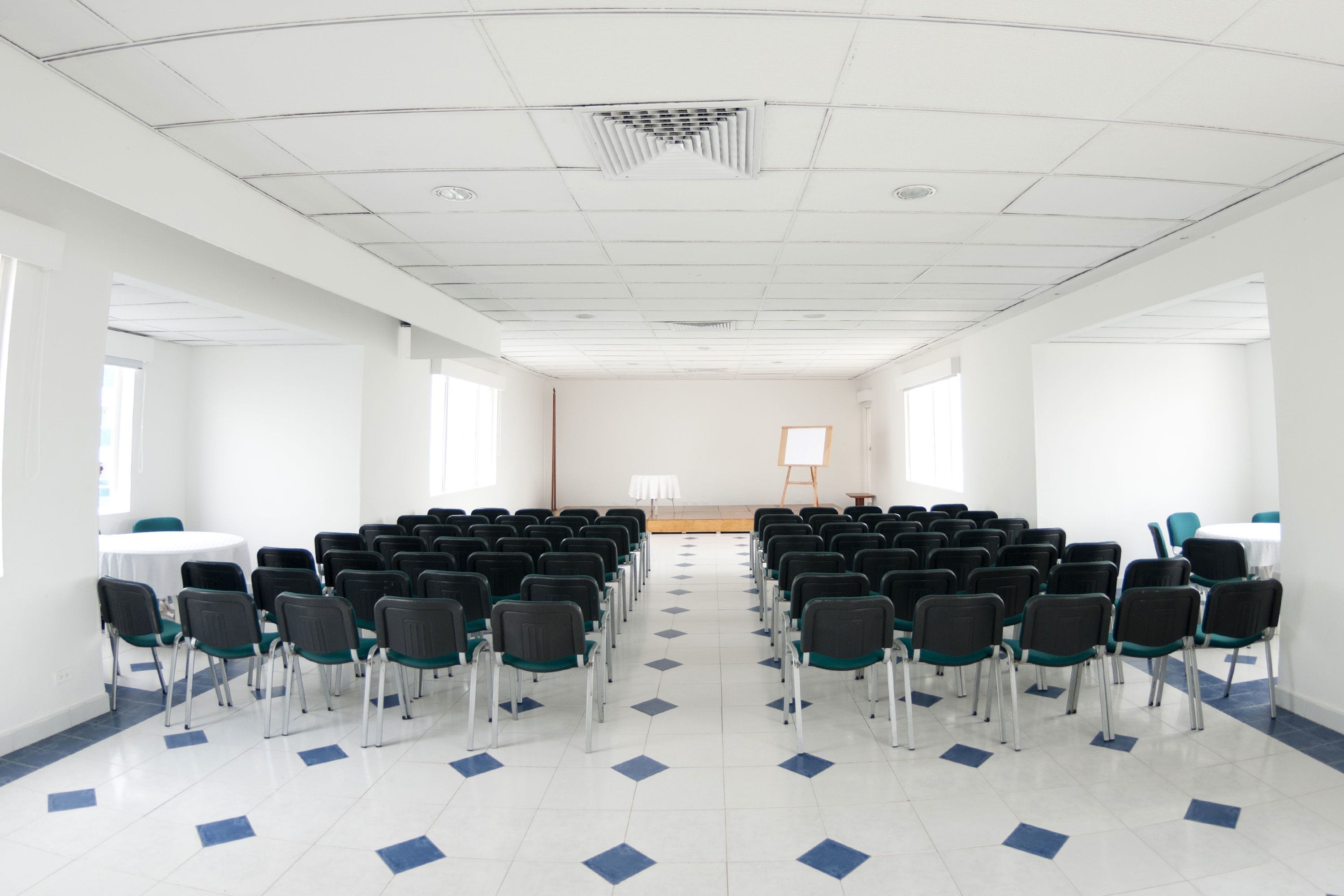 Ein Konferenzraum mit Stuhlreihen, einer Tafel und einer Projektionsleinwand.
