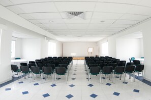 A conference room with rows of chairs, a whiteboard, and a projector screen.