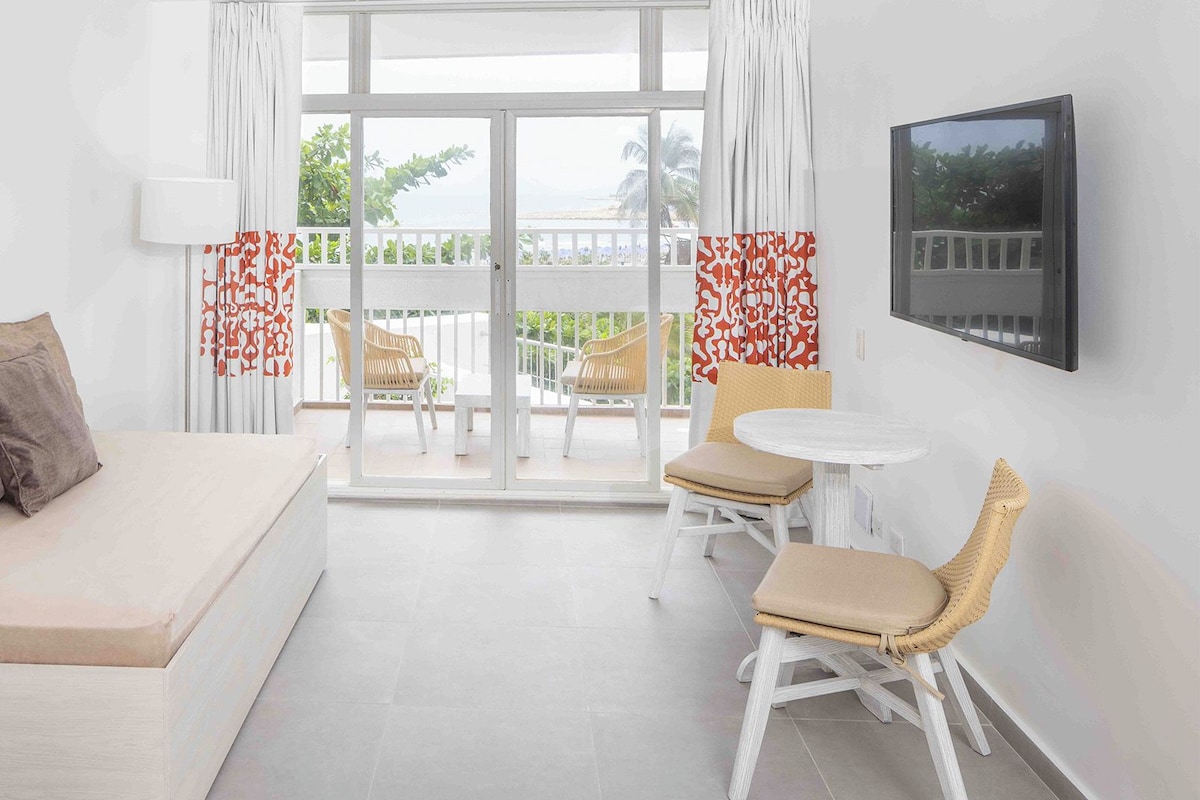 Ein modernes Hotelzimmer mit einem Bett, einem kleinen Tisch, zwei Stühlen und einem Balkon mit Blick.