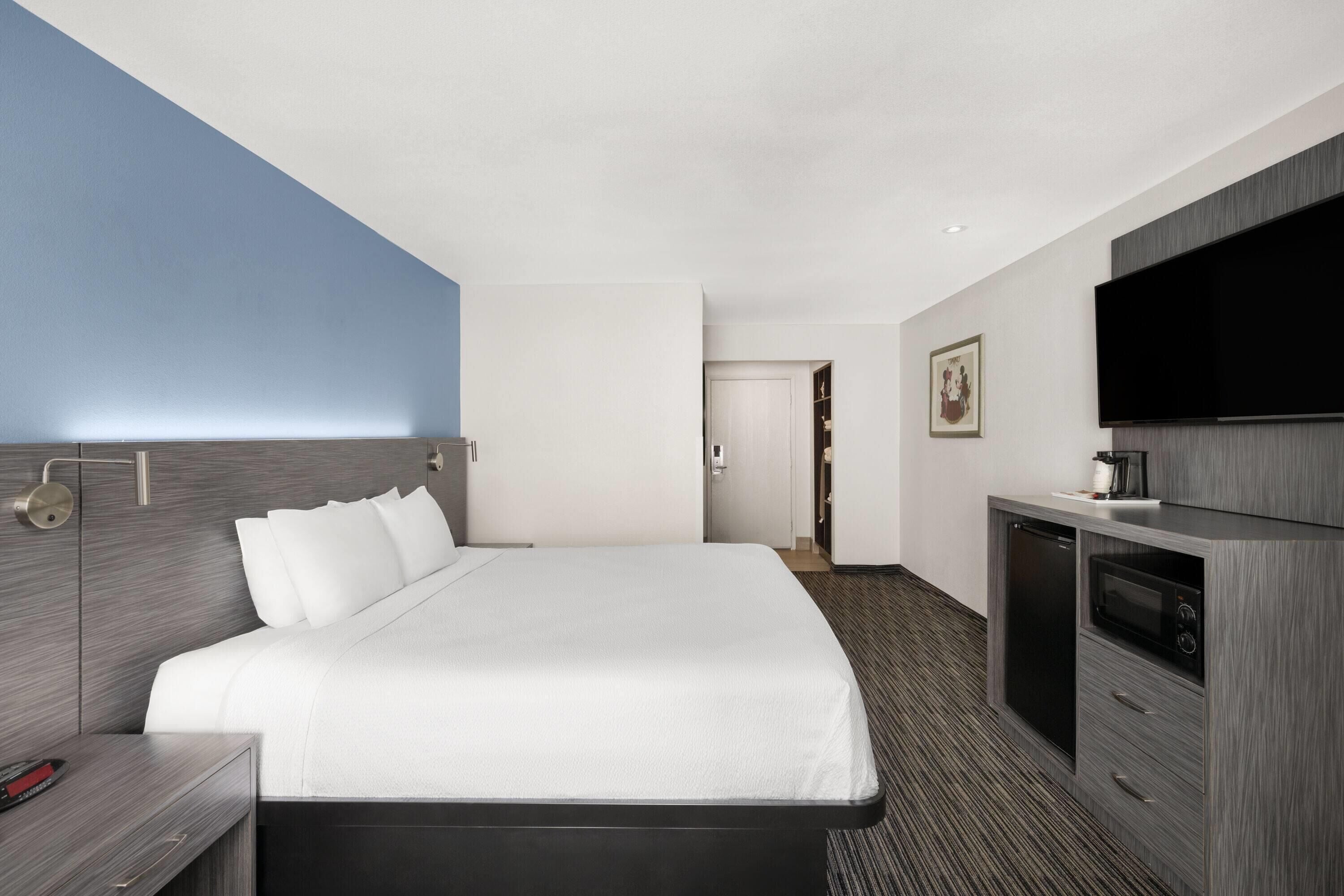 Een moderne hotelkamer met een groot bed, een flatscreen televisie, een ingebouwde magnetron en een kleine kitchenette.