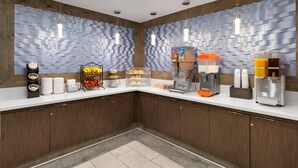 A modern kitchen with wooden cabinets, a white countertop, and a textured wall. There are various appliances and food items on the counter. - Travelodge Inn & Suites by Wyndham Anaheim on Disneyland Dr (Anaheim)
