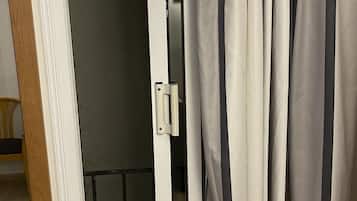 A partially open door with a view into a room that includes a bed and a window.
