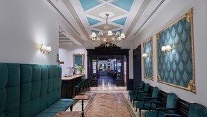 Un hall de hotel con un sofá verde, una zona de bar y una araña.