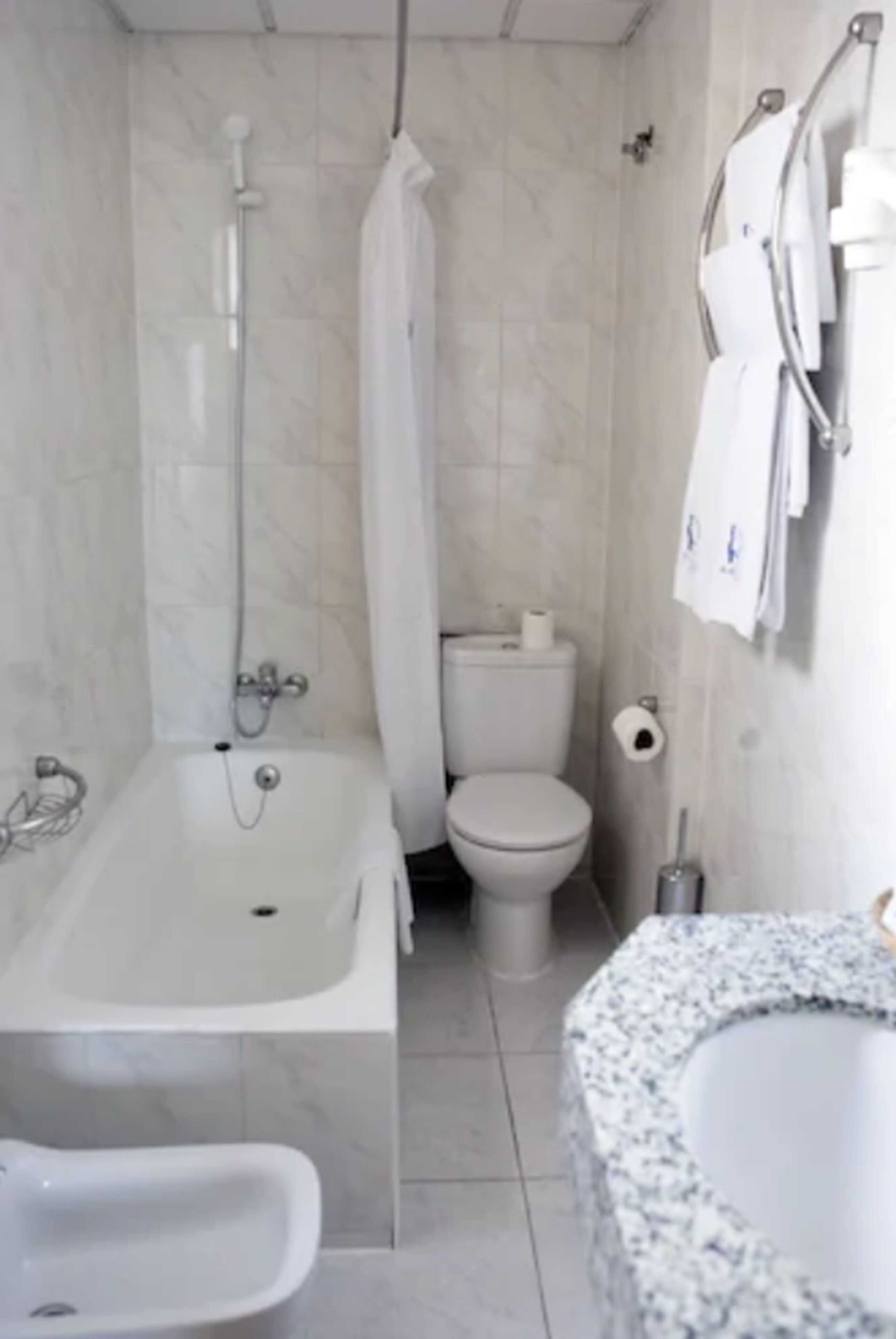 A bathroom with a bathtub, toilet, bidet, and a granite sink.