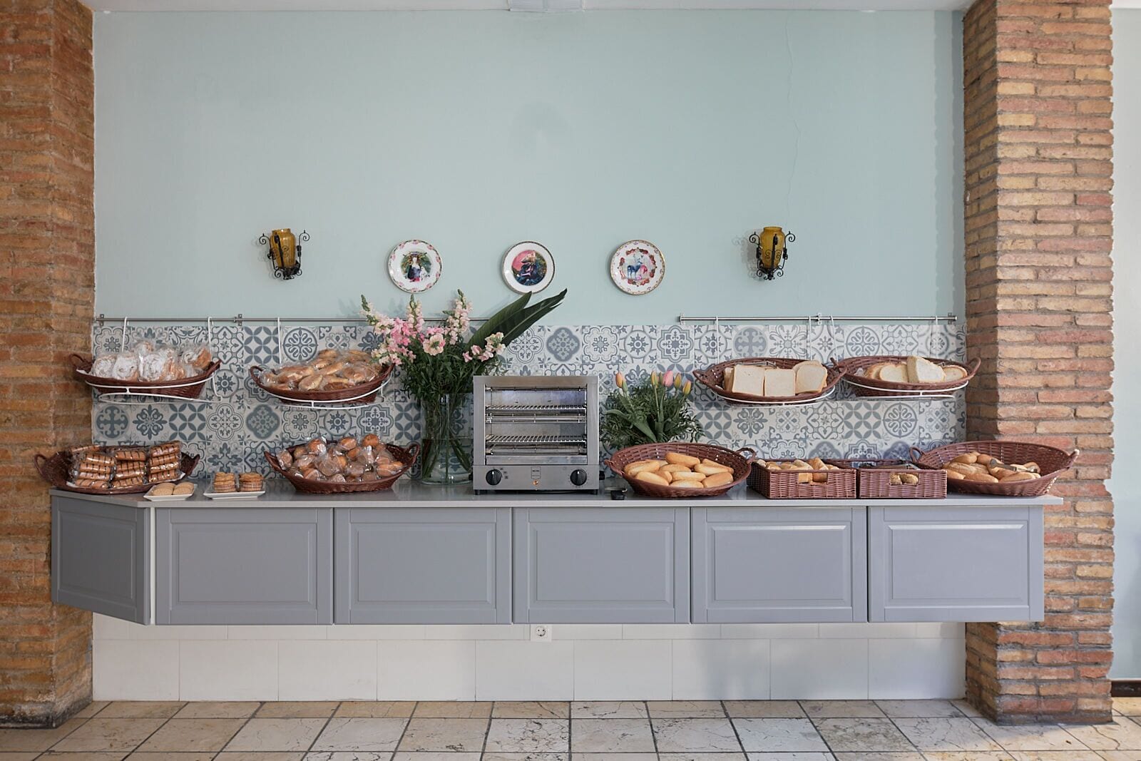 A buffet setup with various food items and decorative plates on a counter against a tiled backsplash.