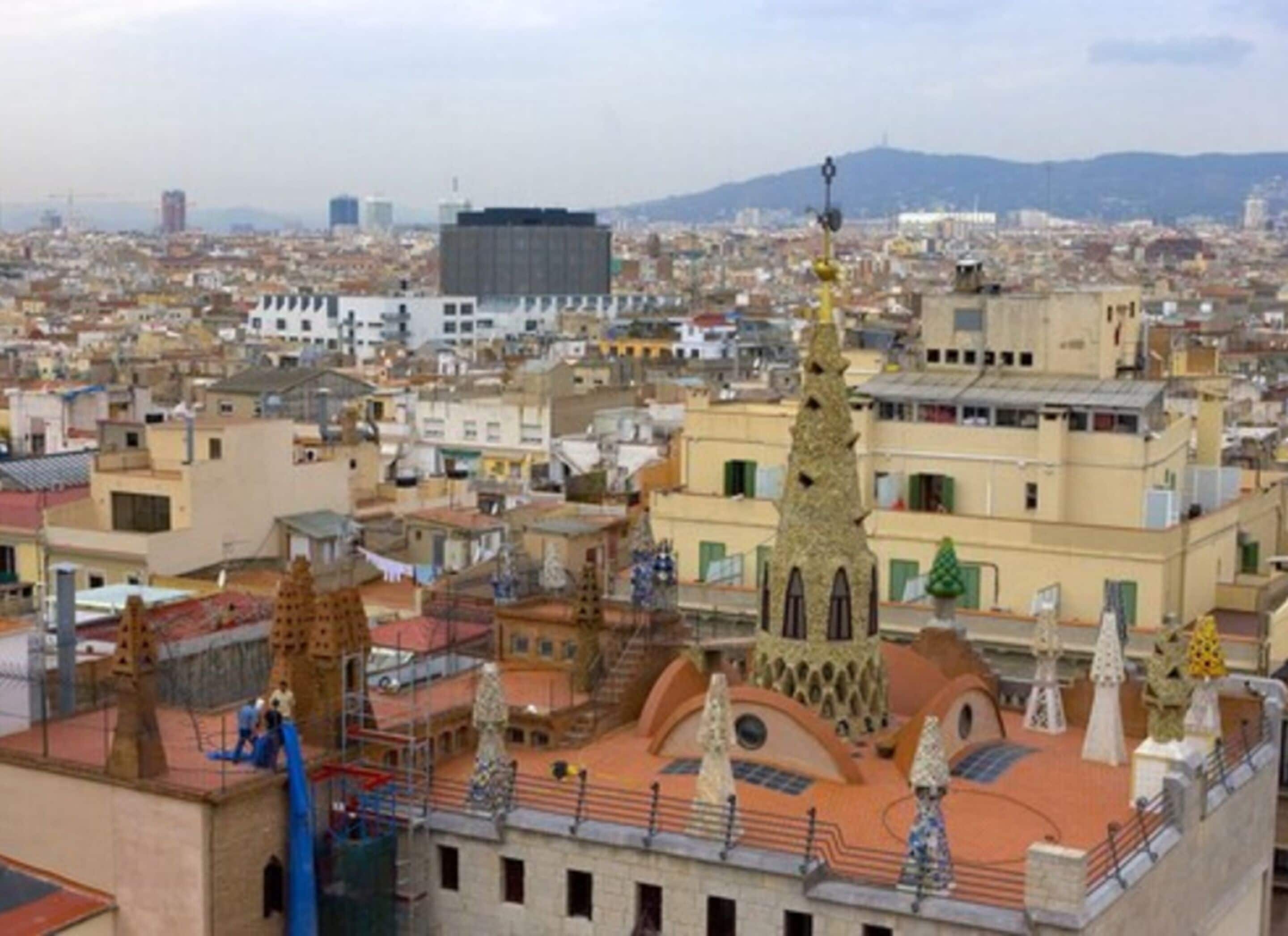 Un paisaje urbano con un edificio destacado que presenta una torre singular y varias construcciones más pequeñas.