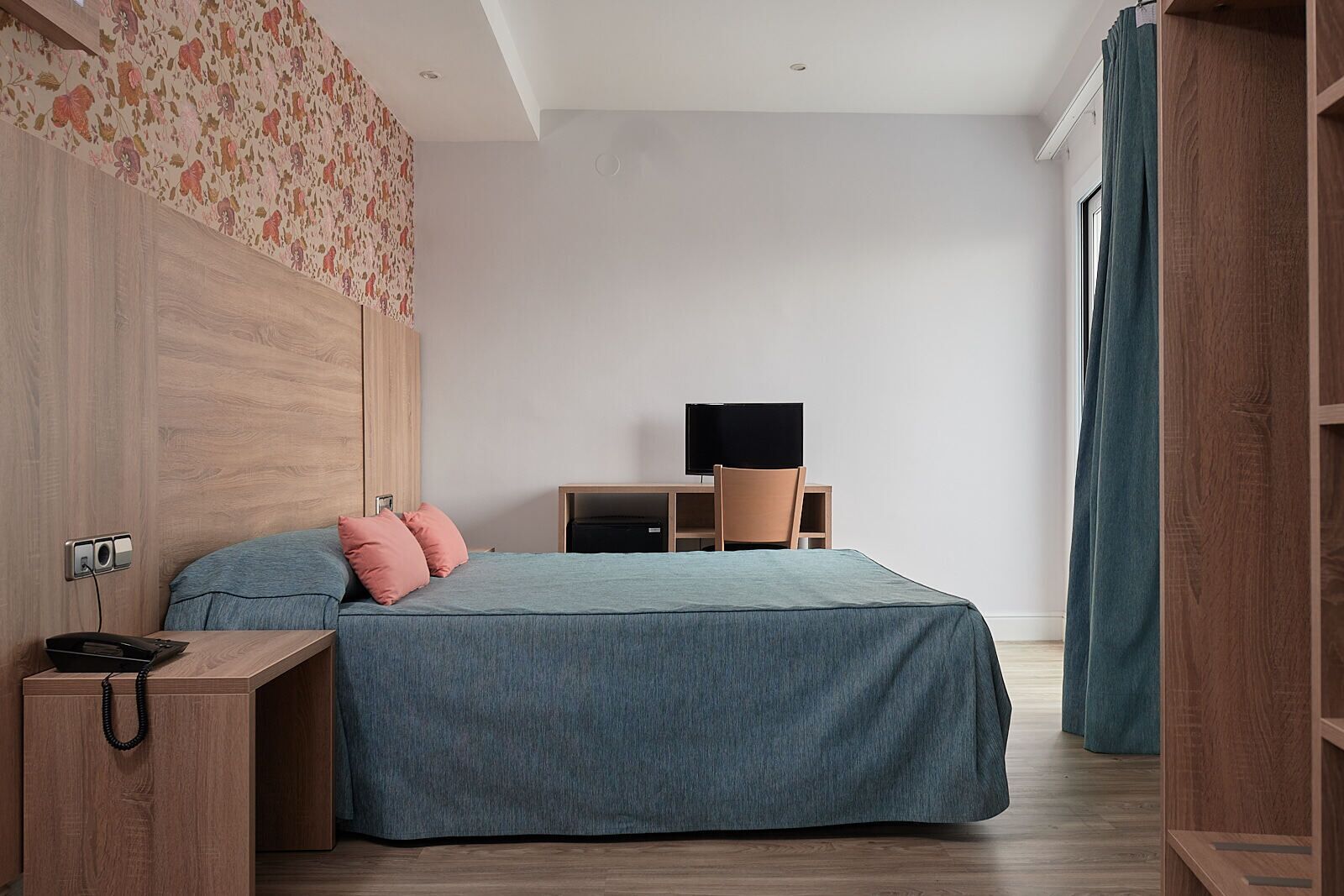 A modern bedroom with a bed, a desk, and a television.