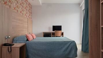 Ein modernes Schlafzimmer mit Bett, Schreibtisch und Fernseher.