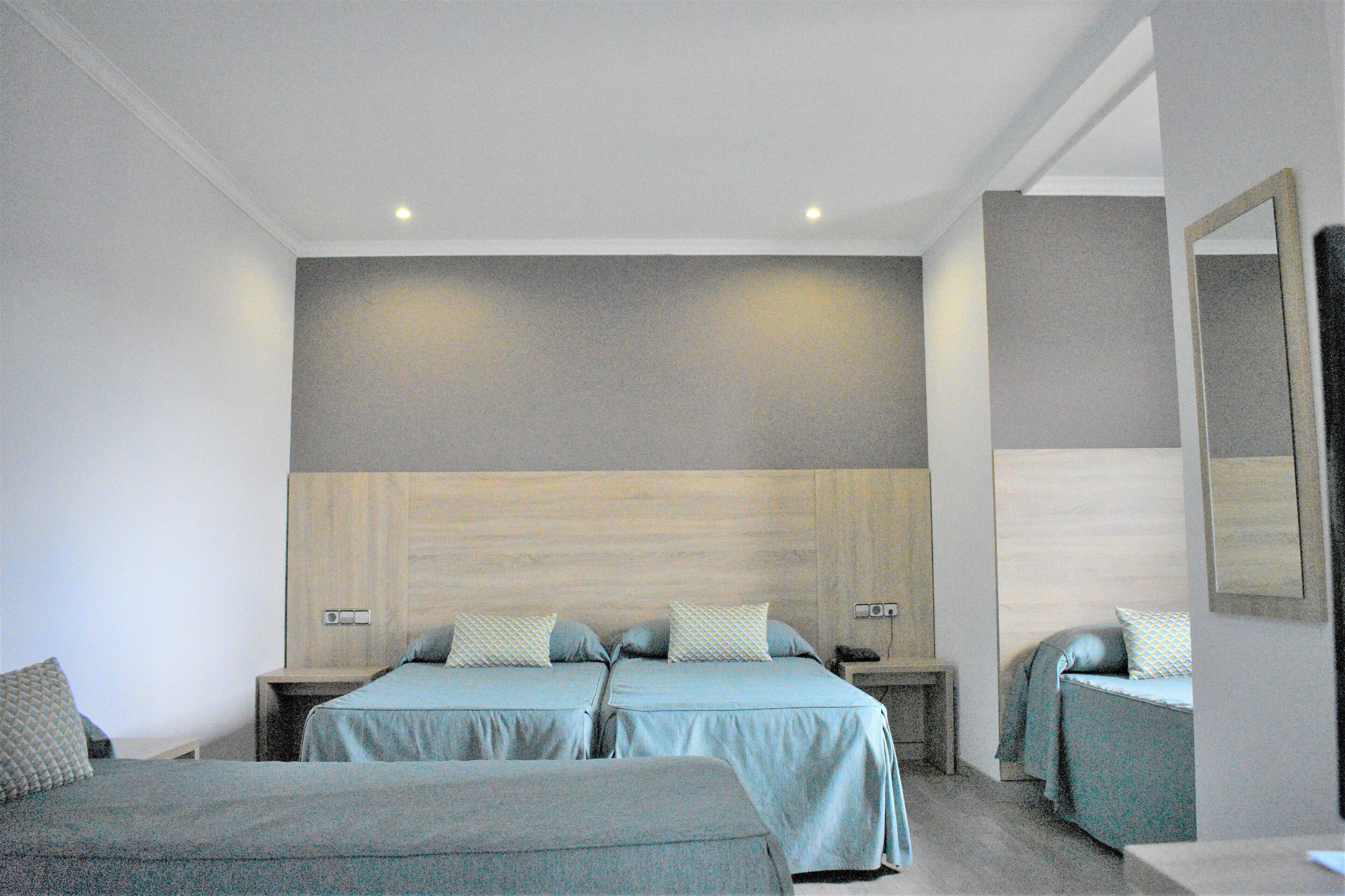 A hotel room with two beds, a wooden headboard, and a large mirror on the wall.