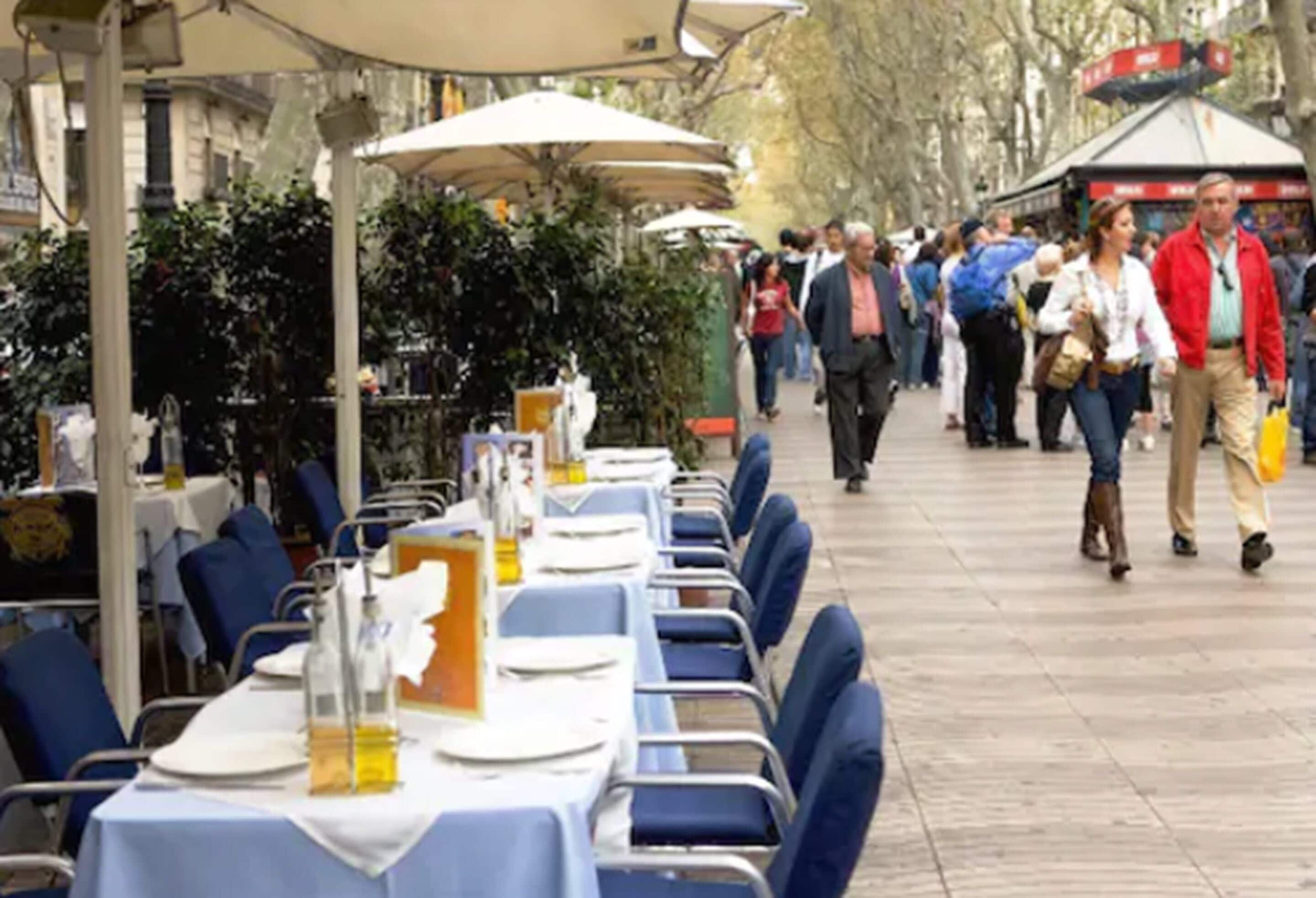 An outdoor dining area with tables and chairs, surrounded by trees and buildings.