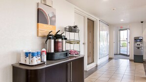 Zona de recepción de un hotel con estación de café, un refrigerador y un basurero.