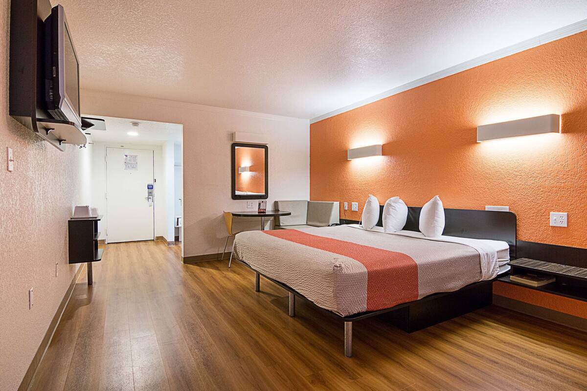 A hotel room with a bed, a desk, a chair, and a television.