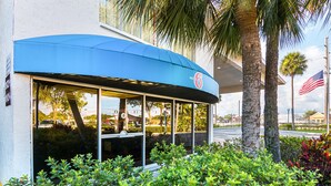 Un motel con toldo azul, palmeras y una bandera estadounidense.