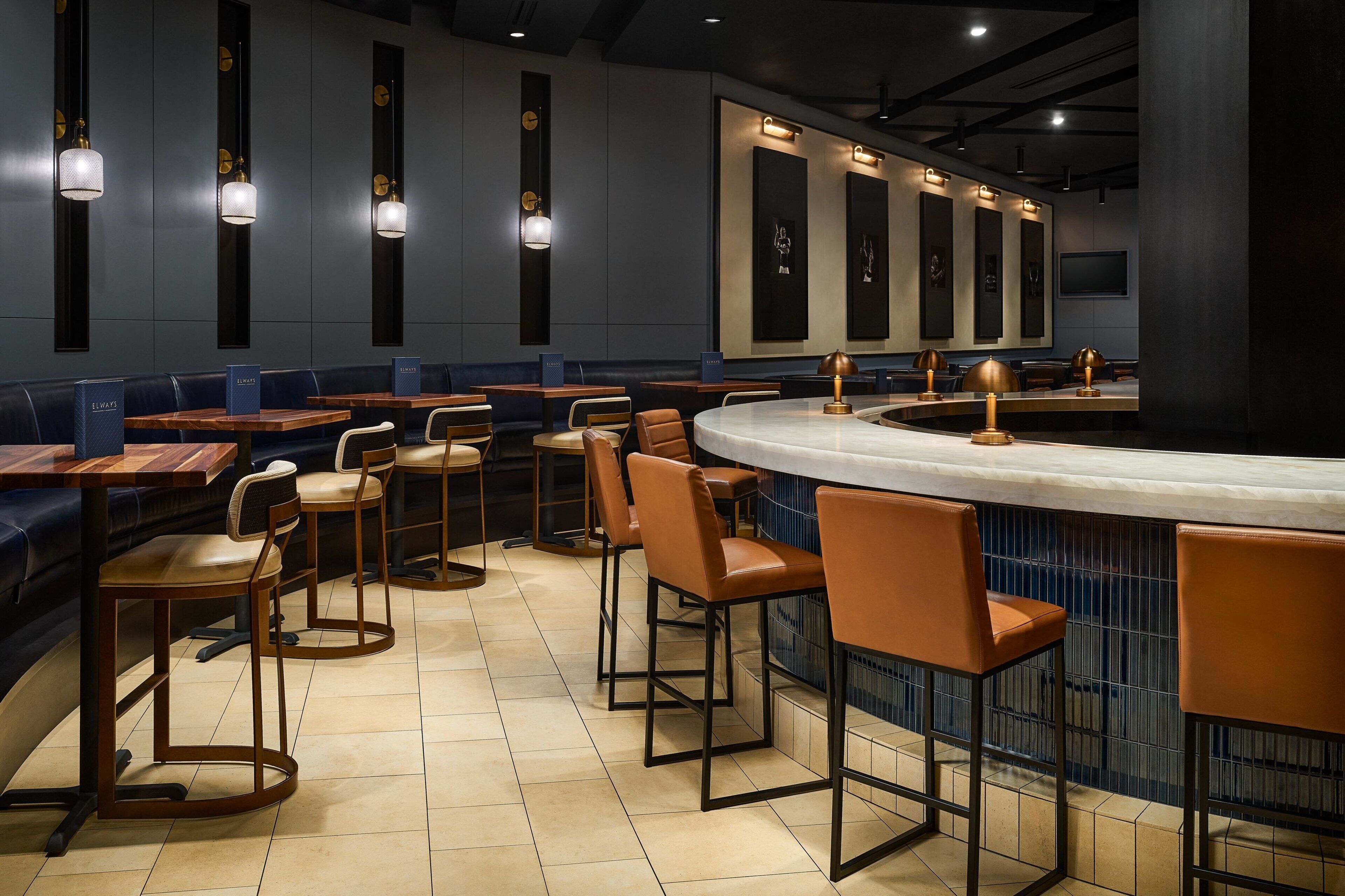 A modern restaurant with a curved bar, high tables, and booths.
