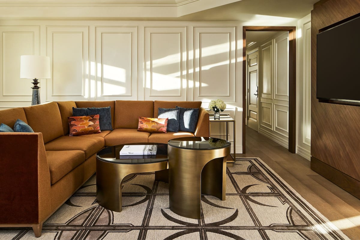 A modern living room with a sectional sofa, two gold side tables, and a patterned rug.
