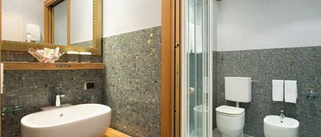 A modern bathroom with a large oval sink, a glass shower enclosure, and a toilet with a bidet.