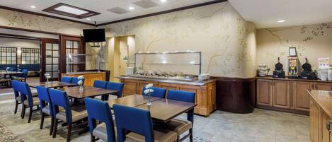 A restaurant with a buffet setup, blue chairs, and a tiled floor.