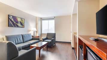 Et moderne hotelværelse med sofa, lænestol, sofabord og et fladskærms-tv.