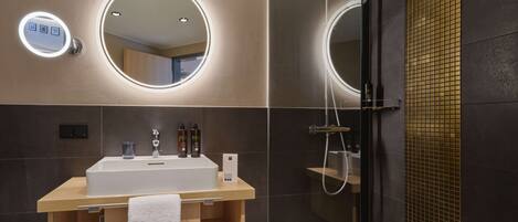 A modern bathroom with a vanity, two illuminated mirrors, and a glass-enclosed shower.