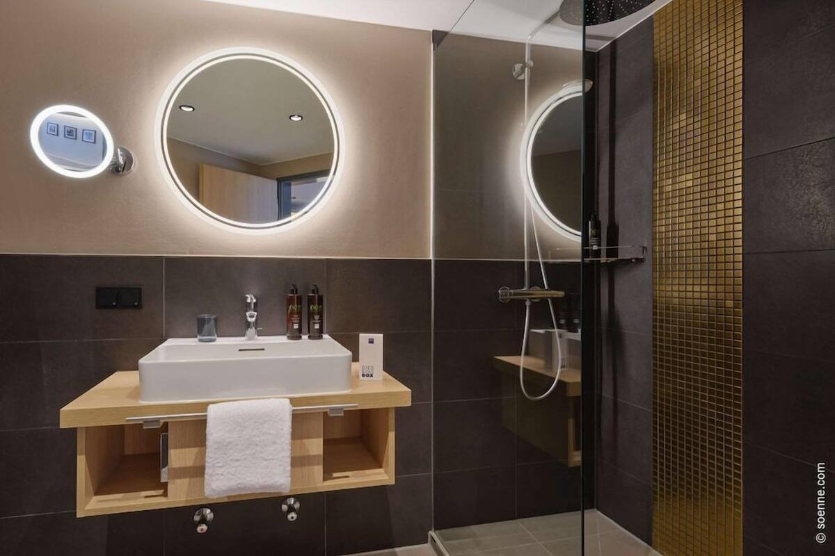 A modern bathroom with a vanity, mirror, and shower.