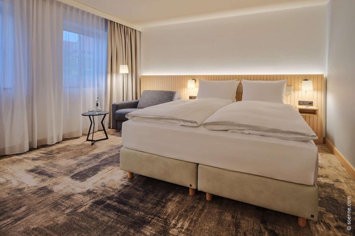 Une chambre d’hôtel avec un grand lit, une petite table, une chaise et une vue sur l’extérieur.