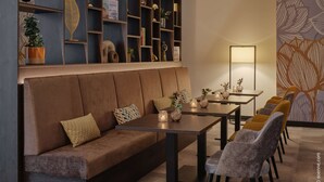 A modern living room with a brown sofa, a coffee table, and a bookshelf filled with books and decorative items. - Dorint Hotel Würzburg (Würzburg)