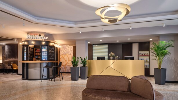 A modern lobby with a reception desk, a bar area, and seating. - Dorint Hotel Würzburg (Würzburg)