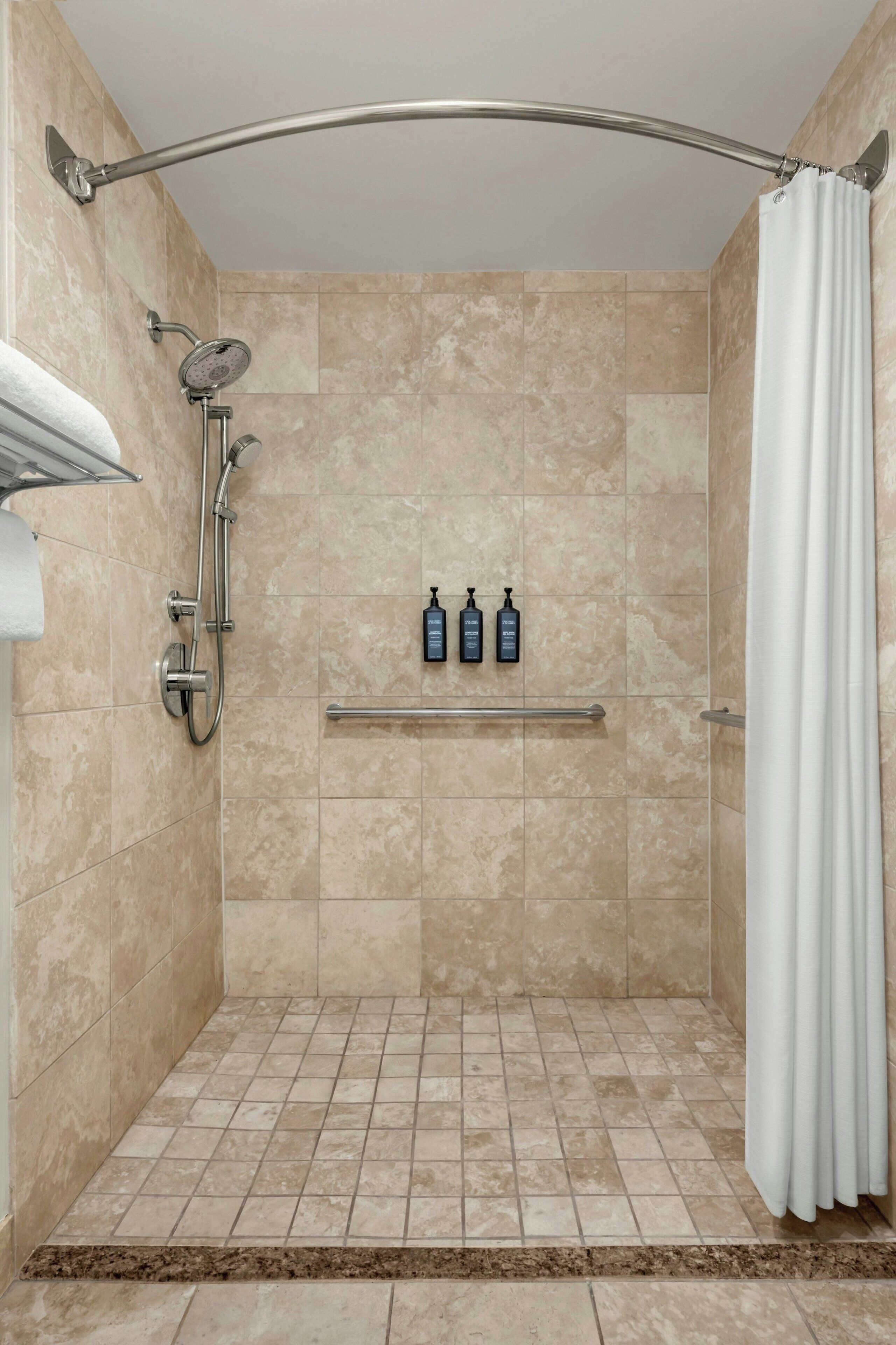 A walk-in shower with beige tiles, a glass door, and a showerhead.
