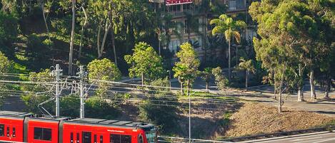 Un tren rojo sobre rieles, con un edificio que dice "Sheraton" al fondo.