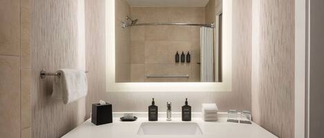 A modern bathroom with a large mirror, a white sink, and a towel rack.